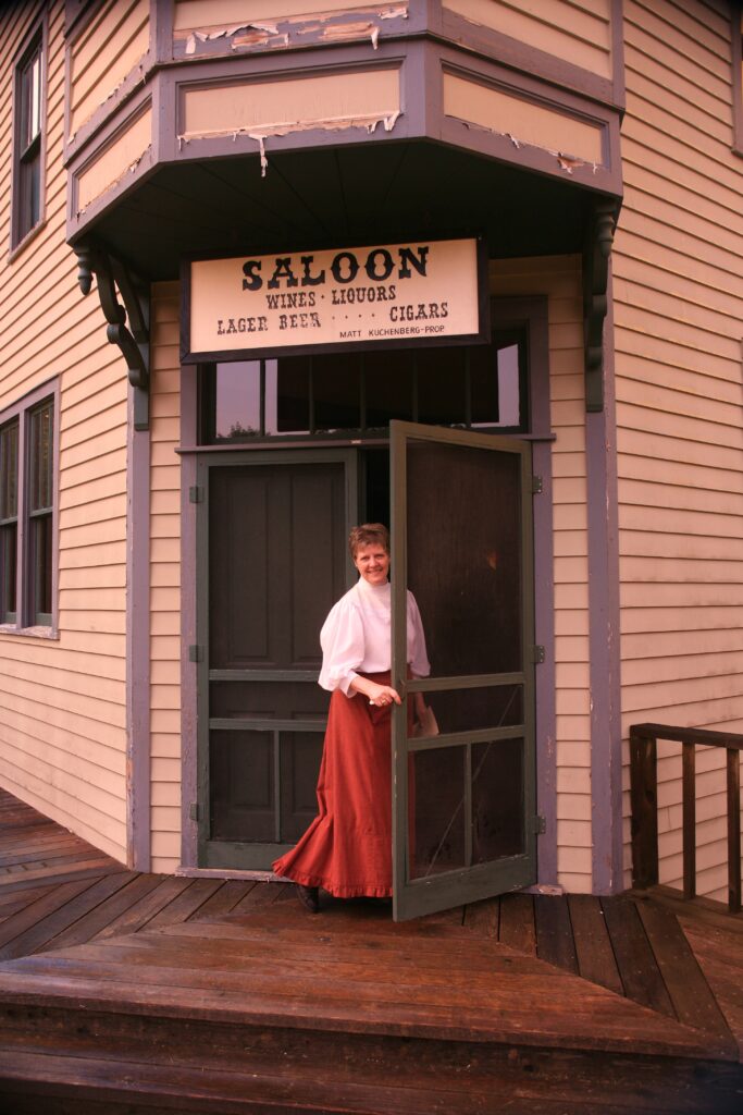 A woman wearing period clothes welcomes guests into the Saloon during  her employment.