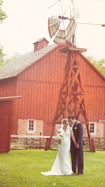 A newly wed couple posing in front of a red barn